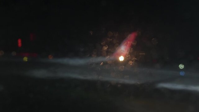 Turkish Airlines airplane wing viewed through a rain-soaked window at night, with blurred lights and reflections visible outside