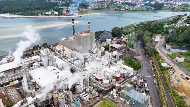 Aerial view of the Ence pulp mill industrial complex with steam rising from chimneys near the river in Pontevedra, Pontevedra, Spain.