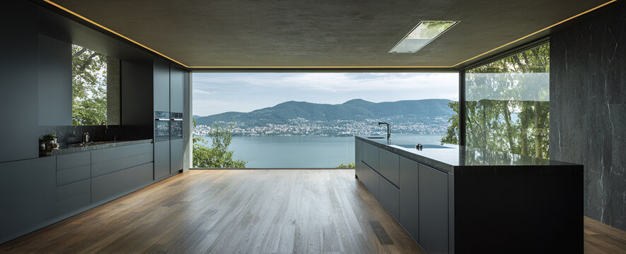 Modern kitchen with large windows overlooking a lake and mountains. Dark cabinetry, wooden floor, and a minimalist design