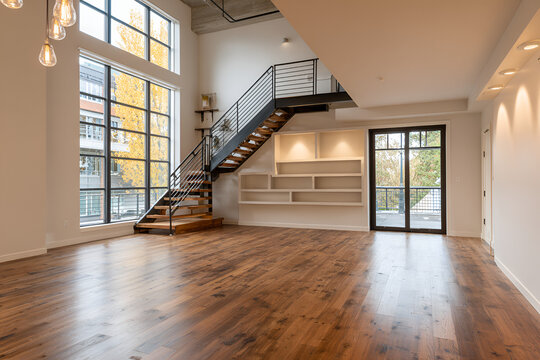 Modern interior featuring hardwood floors, a staircase with metal railings, and large windows with natural light