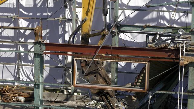 解体工事現場で鉄骨を掴み作業する油圧ショベル
