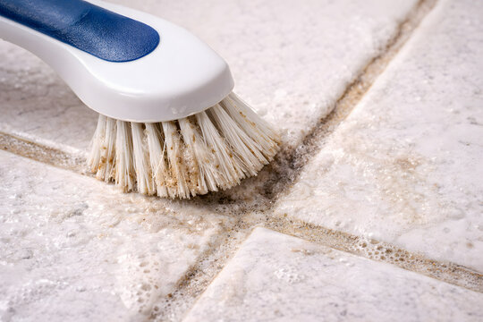 Scrubbing dirty tile grout with cleaning brush and foam close-up