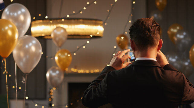 Back, decor and photograph on phone with event organizer at venue for new year party. App, balloons and interior designer man in hall with picture as function coordinator for celebration at night