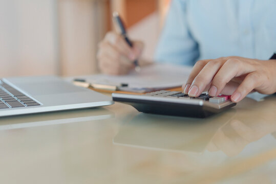 Financial accounting concept businessman calculating corporate tax and budget using calculator writing on clipboard at glass office desk for business investment planning