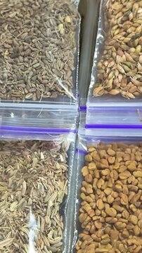 Different aromatic spices such as coriander cumin and assorted seasonings packed in small transparent bags with colorful natural textures for cooking use.