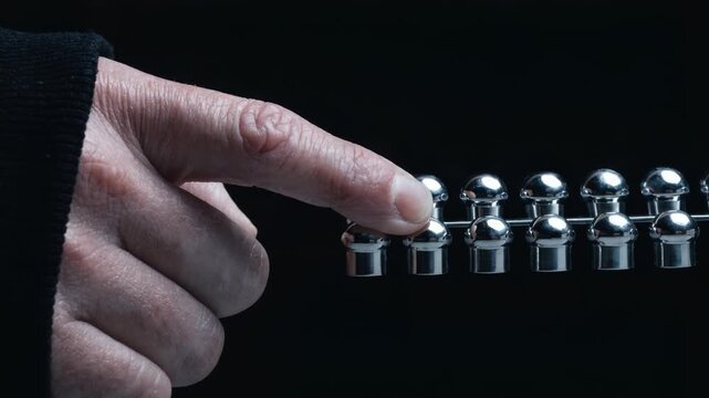 Closeup of a hand interacting with gleaming chrome studs on a dark background, showcasing motion and detail.