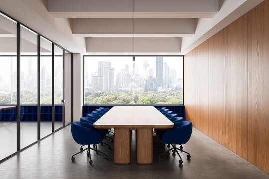Modern conference room with long wooden table, blue chairs, glass walls and skyline view in bright office interior setting. 3D Rendering