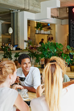 Man, smile and friends in cafe with coffee, social gathering and bonding together on weekend break. Happy, person and group hangout in restaurant with beverage, hospitality and listening to gossip.