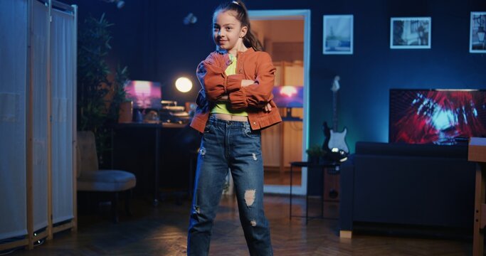 Zoom out shot on little kid mesmerizing her followers with incredible dance moves in neon lit home studio. Cute child showcasing cool dancing skills, filming family friendly content