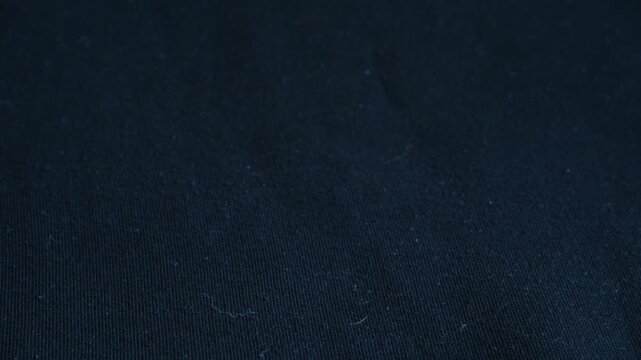 Close up person using sticky lint roller to clean dust, pet hair, dandruff from dark fabric, showing clear before and after effect of cleaning process. Hand using adhesive lint roller on black clothes