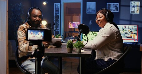 Obraz premium BIPOC influencers in studio using professional camera for internet show production on livestreaming platform. Content creators doing podcasting session with filming gear