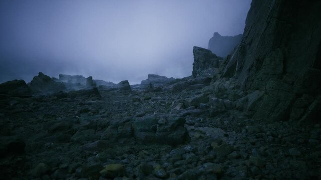 Shrouded shoreline featuring rugged stones and distant rocks. Hazy seaside cliffs dotted with large stones ideal for photographers and hikers