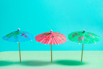 Obraz premium Three Colorful Cocktail Umbrellas on Tropical Summer Background