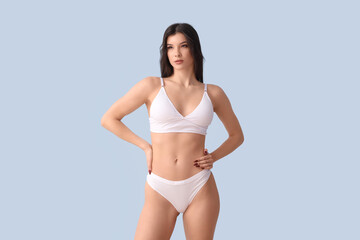 Fototapeta premium Pretty young woman in white underwear on blue background