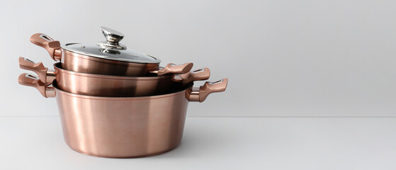 Golden cooking pots on light background © Pixel-Shot