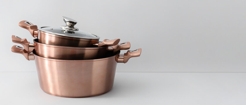 Golden cooking pots on light background
