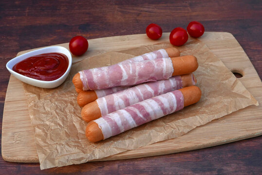 Rohe Berner W&uuml;rstel mit Ketchup auf einem Holzbrett mit Backpapier