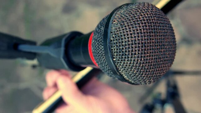 Slow zoom out: POV of a musician playing acoustic guitar in front of a microphone. A singer in front of a microphone. A guitarist strumming a guitar. An artist plucking a guitar. A man playing guitar