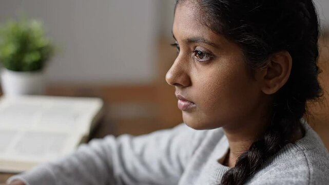 Thoughtful Indian school student concentrating on virtual learning, representing diligent education and intellectual growth for young girls