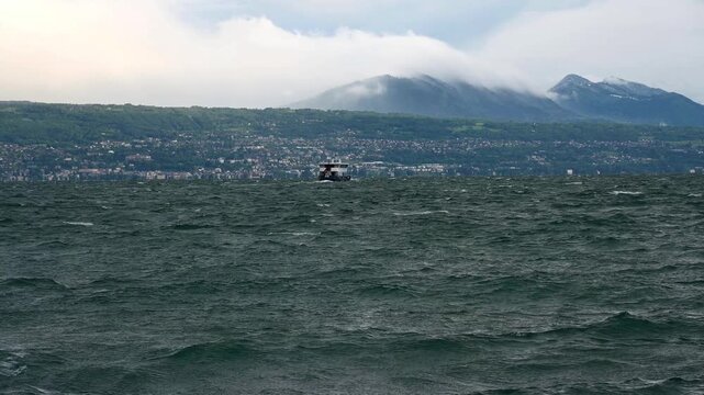 Real Time of Boat on Lake Geneva with Dramatic Waves and Swiss Shoreline in Switzerland.