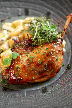 Crispy duck confit served with gnocchi sauce and fresh herbs on elegant restaurant plate