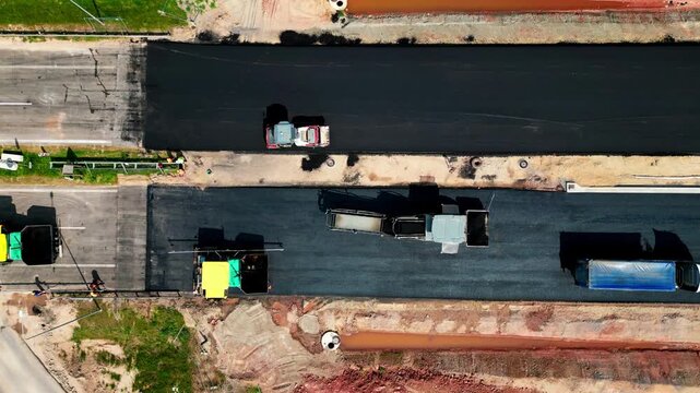 Special construction road equipment repairs or builds a new highway. Reconstruction of roads, laying of asphalt. The Roller lays the road surface. Aerial top view. 4k footage