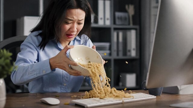 Clumsy Businesswoman Spilling Noodles on Computer Keyboard at Office Desk