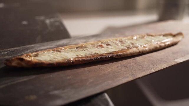 Professional chef preparing a traditional Turkish pide, sprinkling grated cheese on top before baking, fa01