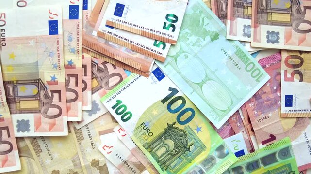 Top view of heap of euro banknotes scattering in slow motion close up.