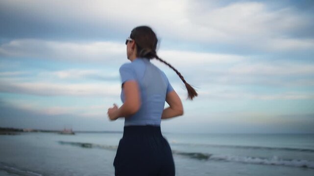 Woman runner training on beach at sunrise near ocean jogging outdoors fitness cardio workout active lifestyle and scenic summer sunset atmosphere