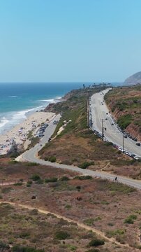 Scenic Pacific Coast Highway in Malibu next to coastline, revealing cars driving along winding road and pristine Southern California landscape