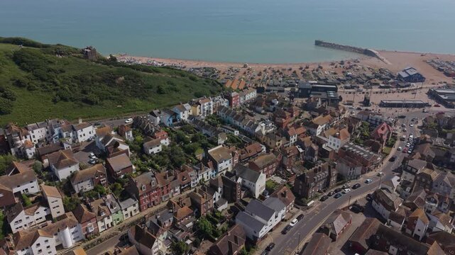 Beautiful Hastings old town with East hill cliff railway and harbor aerial view. Flying above the streets and houses towards famous Stade beach, a historic fishing site. Public park on top of the hill