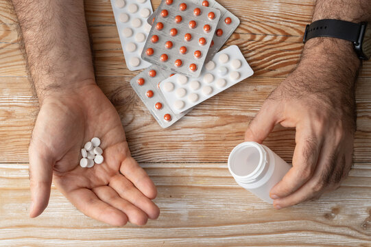 Pills in hand top view, taking painkillers, white medical tablets