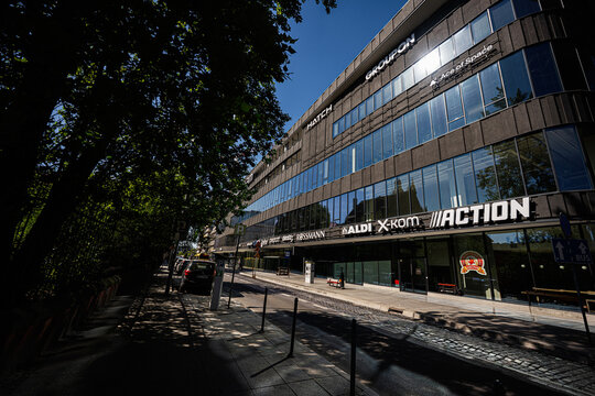 Busy shopping street in Katowice Poland with modern storefronts, pedestrians and urban office building reflecting summer light