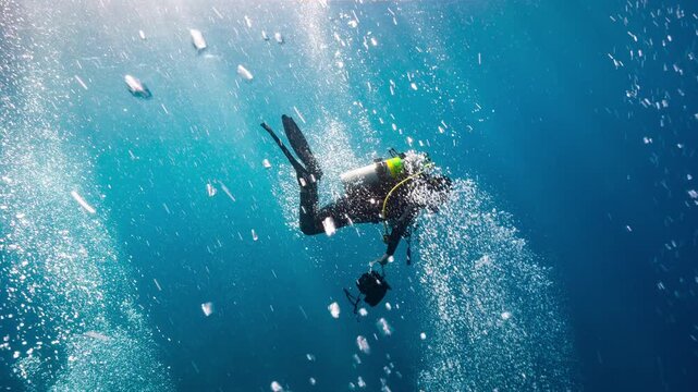 Underwater shot of SCUBA Diver descending through curtain of bubbles at start of dive
