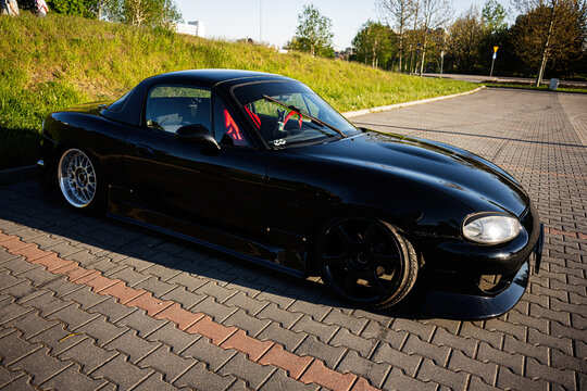 Sleek lowered Mazda MX5 black sports car parked on a brick parking lot in Katowice, Poland with custom wheels and red racing seats