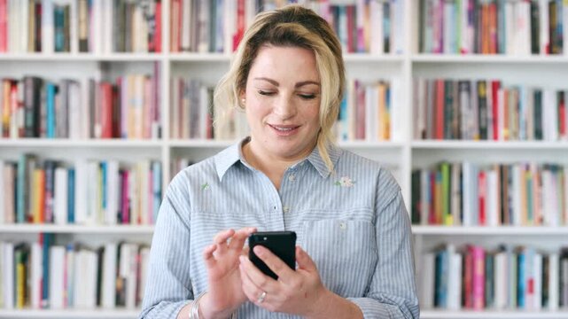 Teacher, research or happy woman with phone in library for academic study, knowledge or information. Female person, professor or scrolling with smile on smartphone for online curriculum or syllabus