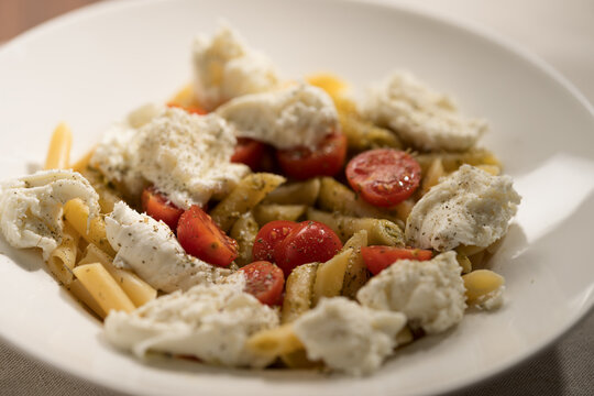Penne pasta with mozzarella, pesto and fresh cherry tomatoes