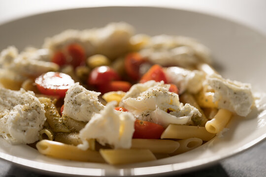 Penne pasta with mozzarella, pesto and fresh cherry tomatoes