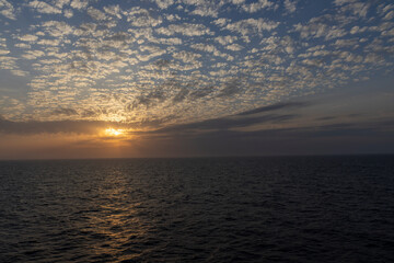 Obraz premium Sunset over open ocean with mackerel sky cloud formation and golden light reflection