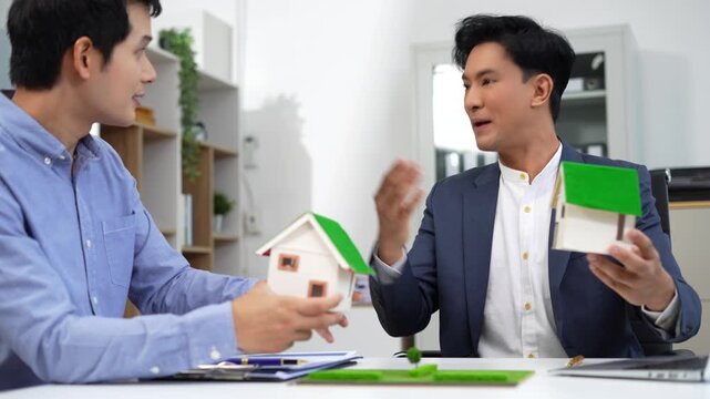Real estate broker agent presenting and consult to customer to decision making sign insurance form agreement, home model, concerning mortgage loan offer in office.