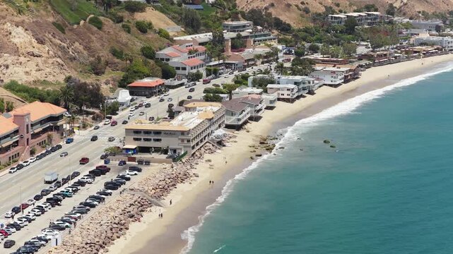Pacific Coast Highway showcasing Malibu Pier and beachside real estate with hillside mansions and coastal homes along beautiful sandy shore and ocean waves