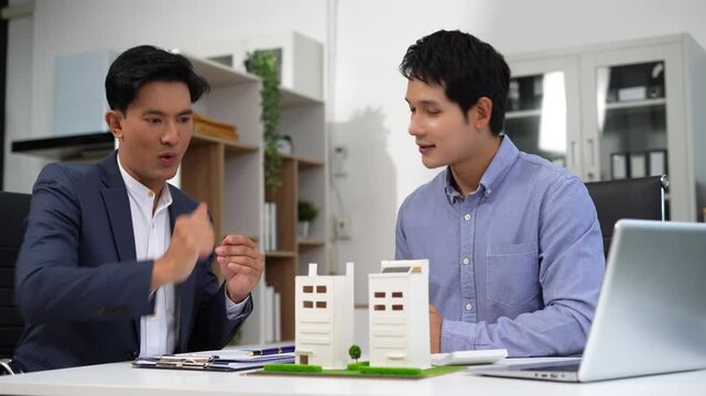Real estate broker agent presenting and consult to customer to decision making sign insurance form agreement, home model, concerning mortgage loan offer in office.