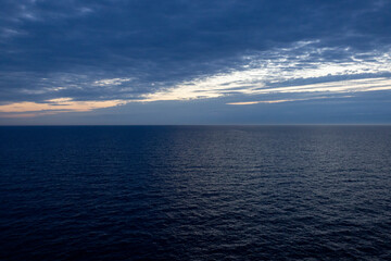 Fototapeta premium Calm open ocean horizon under cloudy twilight sky at dusk
