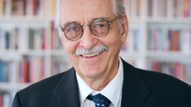 Smile, professor and face of man in library for about us, course lecturer and faculty manager. Education, university dean and bookshelf with mature person for pride, teacher and college advisor