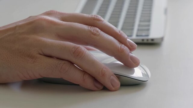 Close-up of a person's hand using a computer mouse and keyboard for work or study