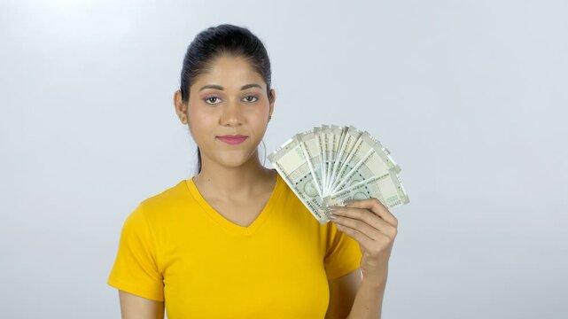 Young Indian girl proudly showing her last month's salary - financial planning. Medium shot of a confident-looking female holding five hundred rupee banknotes saved from her earnings