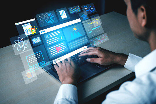 Man using laptop with futuristic holographic interface displaying data analytics, charts, and technology visuals in a modern workspace environment. Entropy.