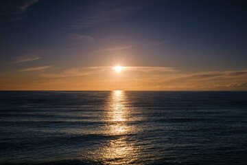 Fototapeta premium Beautiful golden sunset over the calm sea horizon with sun reflecting on water.