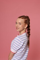 Obraz premium Portrait of smiling teenage girl with beautiful braids on pink background
